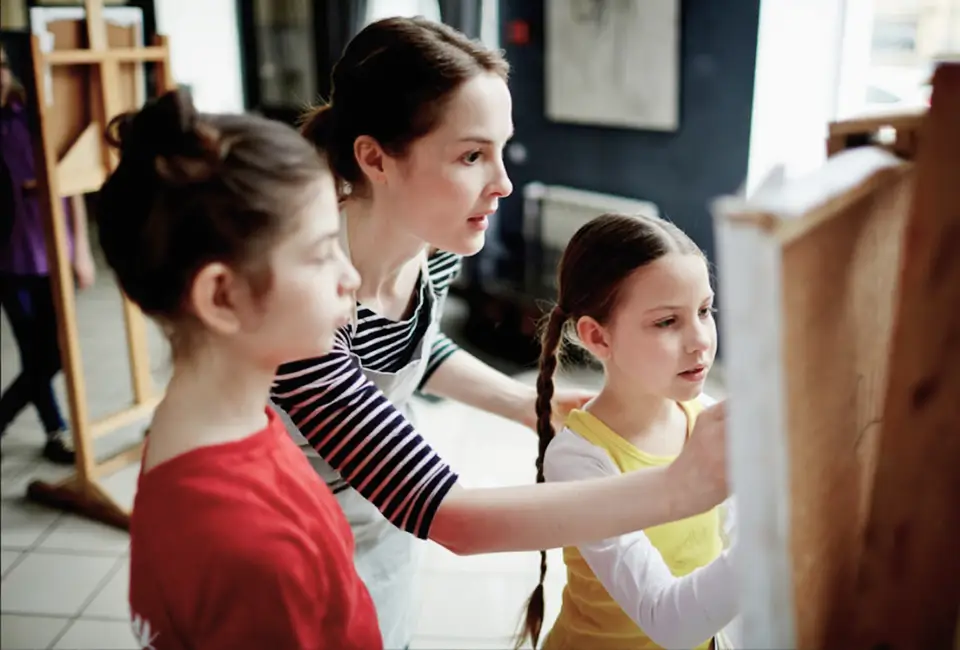 Çocuklara resim eğitiminde yardımcı olan bayan hoca