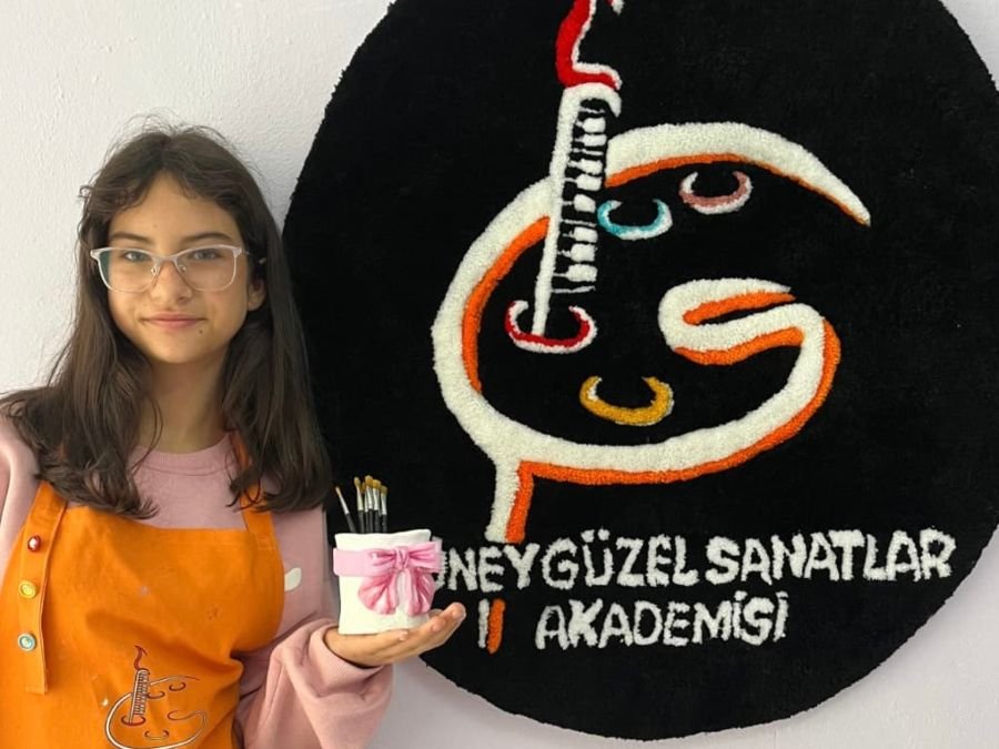 Mutlu bitmiş seramik obje tutan öğrenci