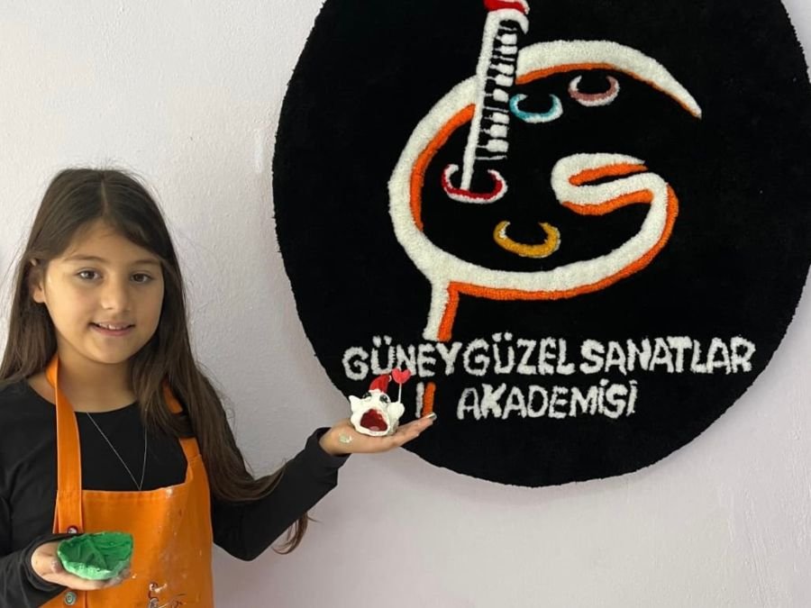 Mutlu bitmiş seramik objeler tutan öğrenci