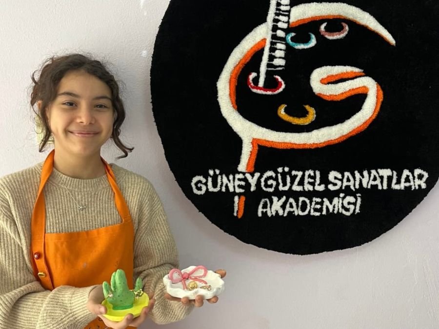 Mutlu bitmiş seramik objeleri tutan öğrenci