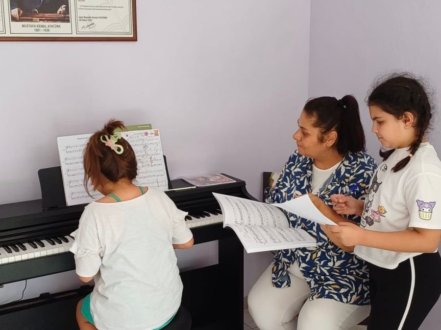 Öğretmen öğrencilere piyano öğretiyor